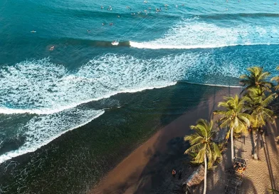 Aerial view of Arugam Bay's famous Main Point surf break, showing powerful waves and numerous surfers in the ocean, highlighting the popular surfing scene as a primary things to do in Arugam Bay attraction.