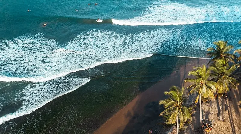 Aerial view of Arugam Bay's famous Main Point surf break, showing powerful waves and numerous surfers in the ocean, highlighting the popular surfing scene as a primary things to do in Arugam Bay attraction.