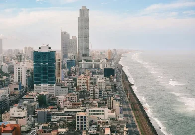 An aerial view of the modern Colombo city skyline, high-rise buildings, and the railway line running along the ocean, showcasing things to do in Colombo.