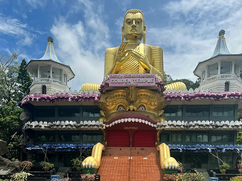 The colossal golden Buddha statue and golden demon mouth entrance of the Dambulla Golden Temple, a key cultural and religious site among things to do in Dambulla