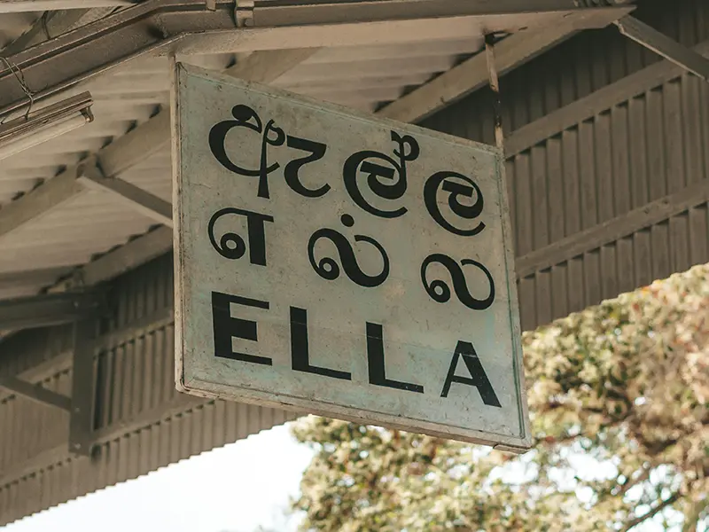 The white and black sign for Ella Railway Station in Sinhalese and English, marking the start of many things to do in Ella.