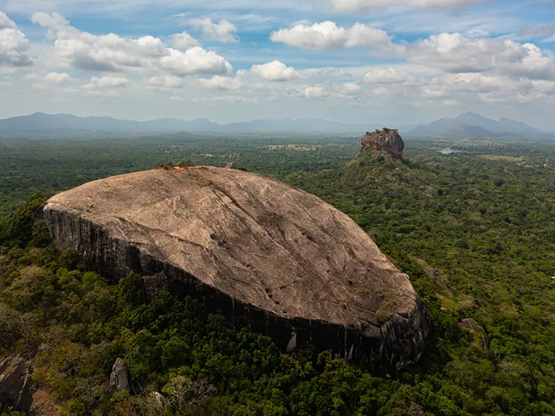 Panoramic view from Pidurangala Rock, showcasing the massive Sigiriya Lion Rock Fortress rising dramatically from the jungle, providing the best photographic viewpoint for things to do in Sigiriya.