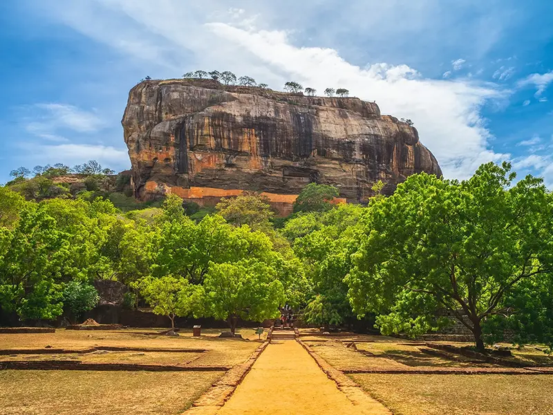 The magnificent Sigiriya Lion Rock Fortress rising above the ancient water gardens, highlighting the climb and historical site, one of the top things to do in Sigiriya.