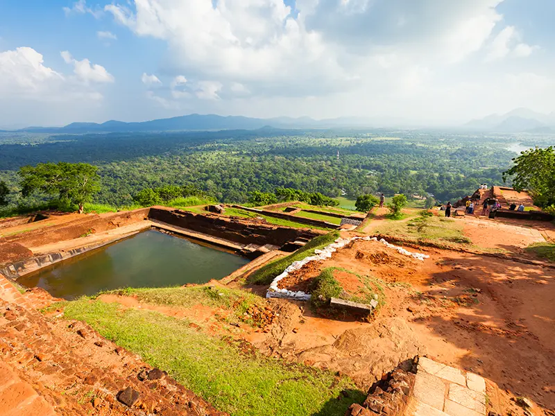 Panoramic view from the summit of Sigiriya Lion Rock, showing the ancient palace ruins, the rock-cut pool, and the vast jungle landscape below, the rewarding final stage of climbing Sigiriya