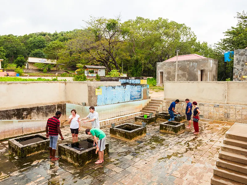 Visitors using buckets to take water from the seven square-shaped wells at the Kanniya Hot Springs in Trincomalee, a site revered for its warm, therapeutic water and historical connection to the Ramayana epic.