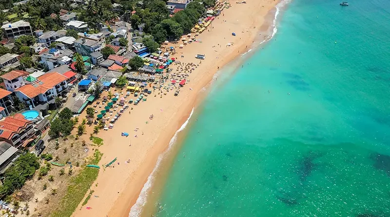 Aerial view of Unawatuna Beach, showing the vibrant crescent of golden sand, turquoise water, and the densely built-up shoreline of the main town, a popular destination for things to do in Unawatuna, Sri Lanka.
