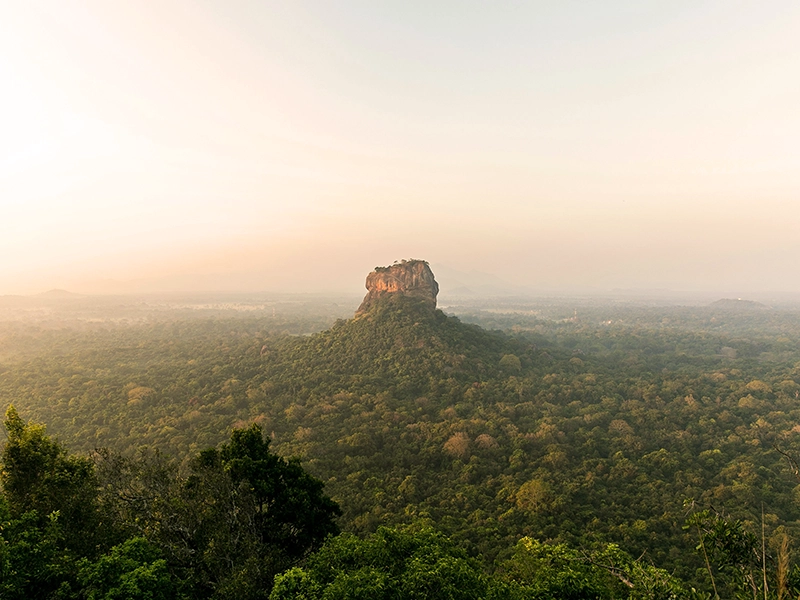 A breathtaking sunset view of Sigiriya Rock Fortress as seen from Pidurangala Rock, highlighting one of the best places to visit in Sri Lanka on your 2 week Sri Lanka itinerary.